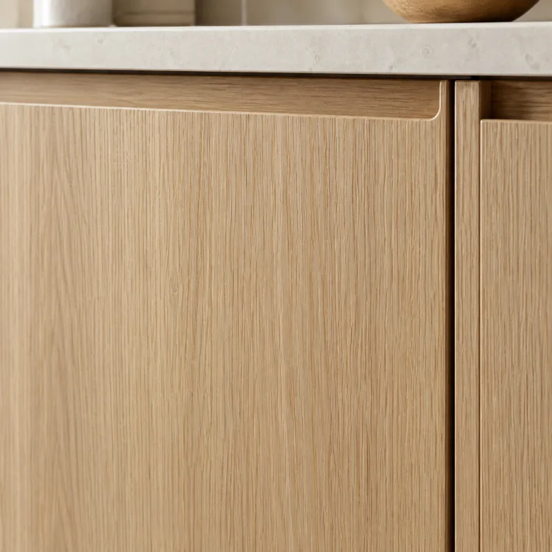 Close-up of a rift-sawn white oak cabinet door with a straight pale grain, a matte natural finish, and a finger-pull edge